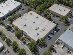 Oblique aerial image of commercial buildings and parking lots, with orange outlines tracing the roofs of two buildings.