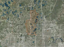 Satellite map of a suburban area with an elongated irregular territory outlined in orange.