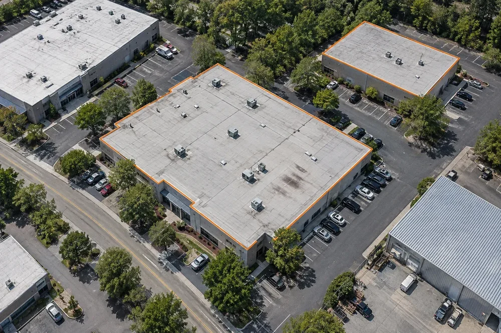 Oblique aerial image of commercial buildings and parking lots, with two building footprints outlined in orange.