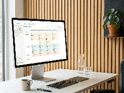Desktop monitor on an office desk displaying a weekly calendar with color-coded shift assignments.