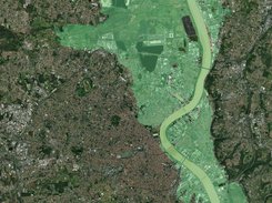 Satellite image of a city and river with a translucent green polygon overlay covering the riverside area.