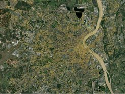 Satellite map of a city beside a river with an extensive yellow road-network overlay.