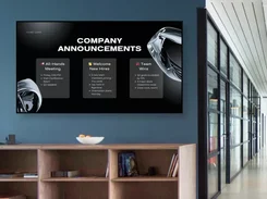 Office hallway display shows an ACME Corp. company announcements board with meeting, new-hire, and team-win cards.